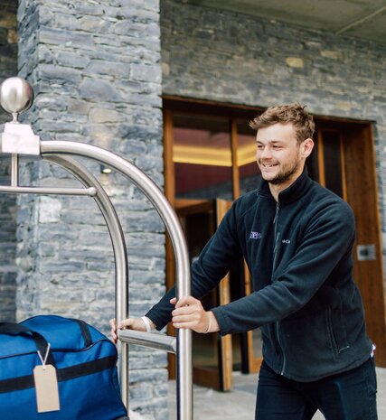 Smiling hotel host moving bags outside Bear Lodge
