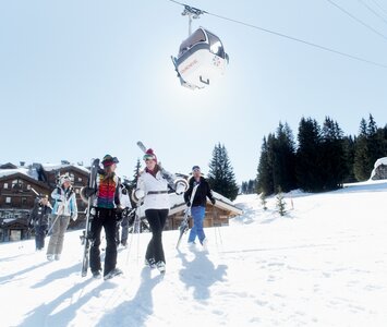 Skiers walking across ski slope carrying skis
