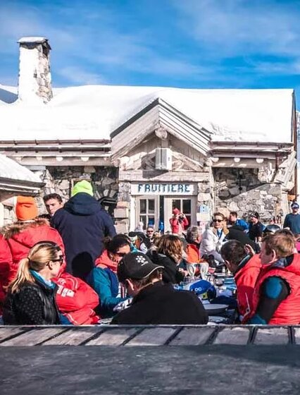 Outside seating area of La Fruitiere in Val d'Isere with lots of people sitting at tables in ski wear